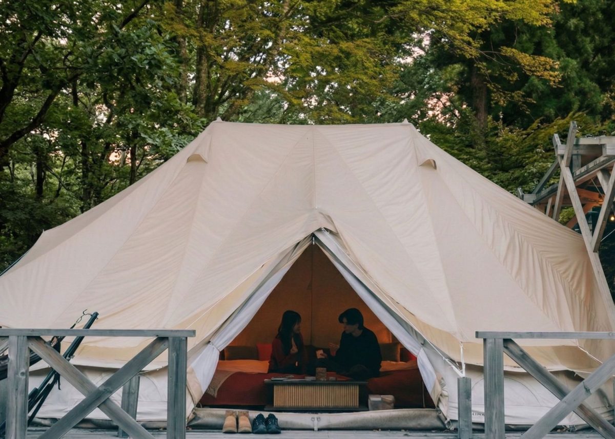 グランピング施設で皇帝テントの中でカップルがくつろいでいる様子